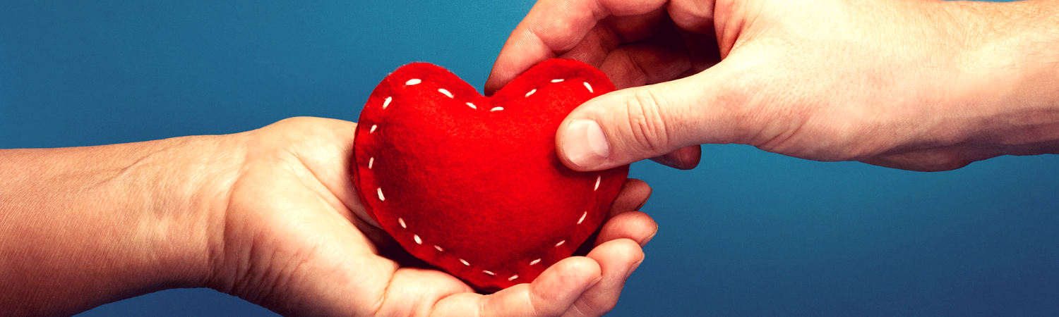 Hand Placing Heart in Another Hand